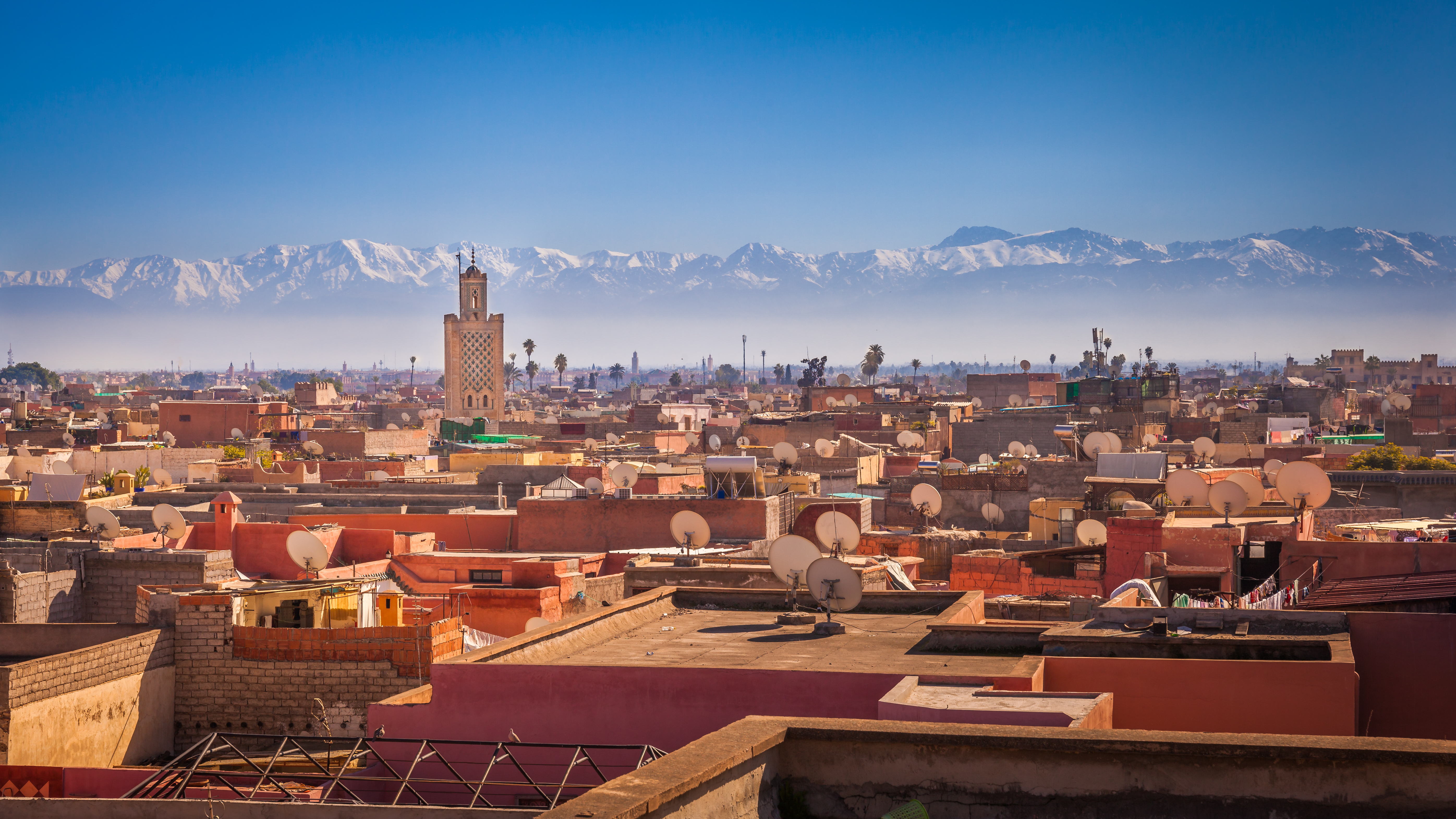 Panoramaudsigt over Marrakesh med traditionel arkitektur og sneklædte Atlasbjerge i baggrunden, Marokko