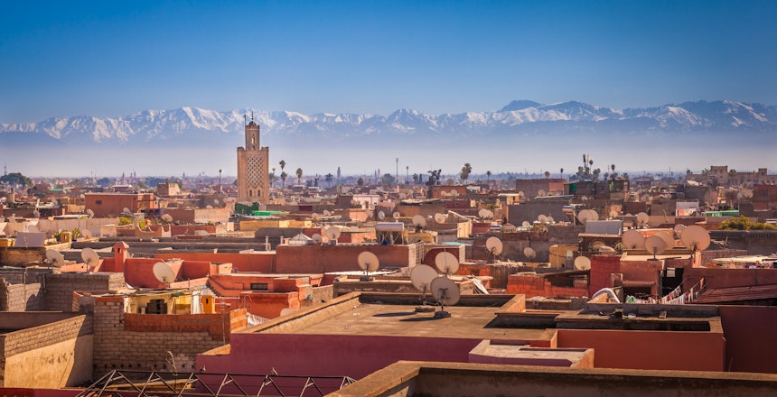 Panoramaudsigt over Marrakesh med traditionel arkitektur og sneklædte Atlasbjerge i baggrunden, Marokko