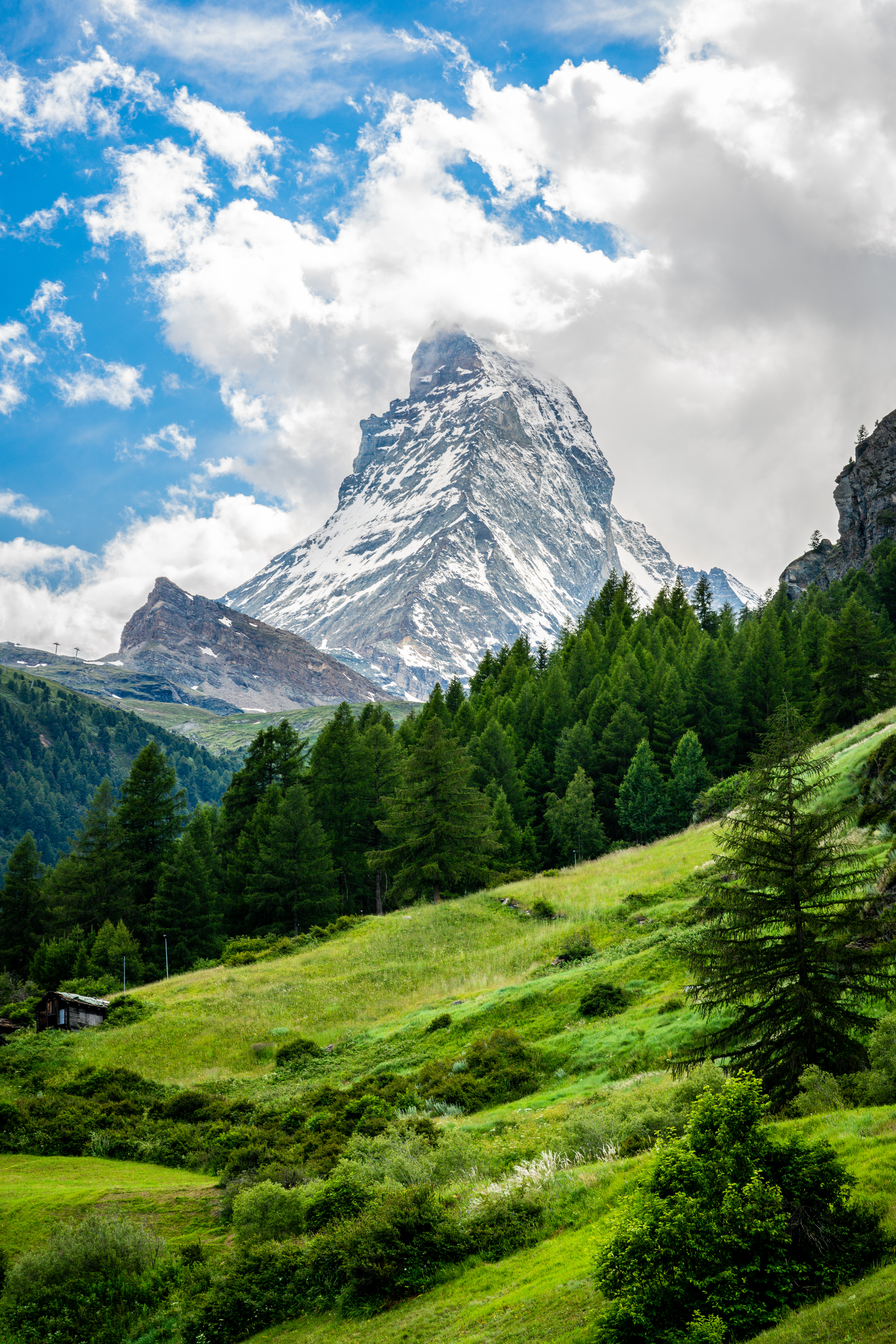 Det majestætiske Matterhorn-bjerg med sneklædt top og frodige grønne alper i sommersolskin i Zermatt, Schweiz