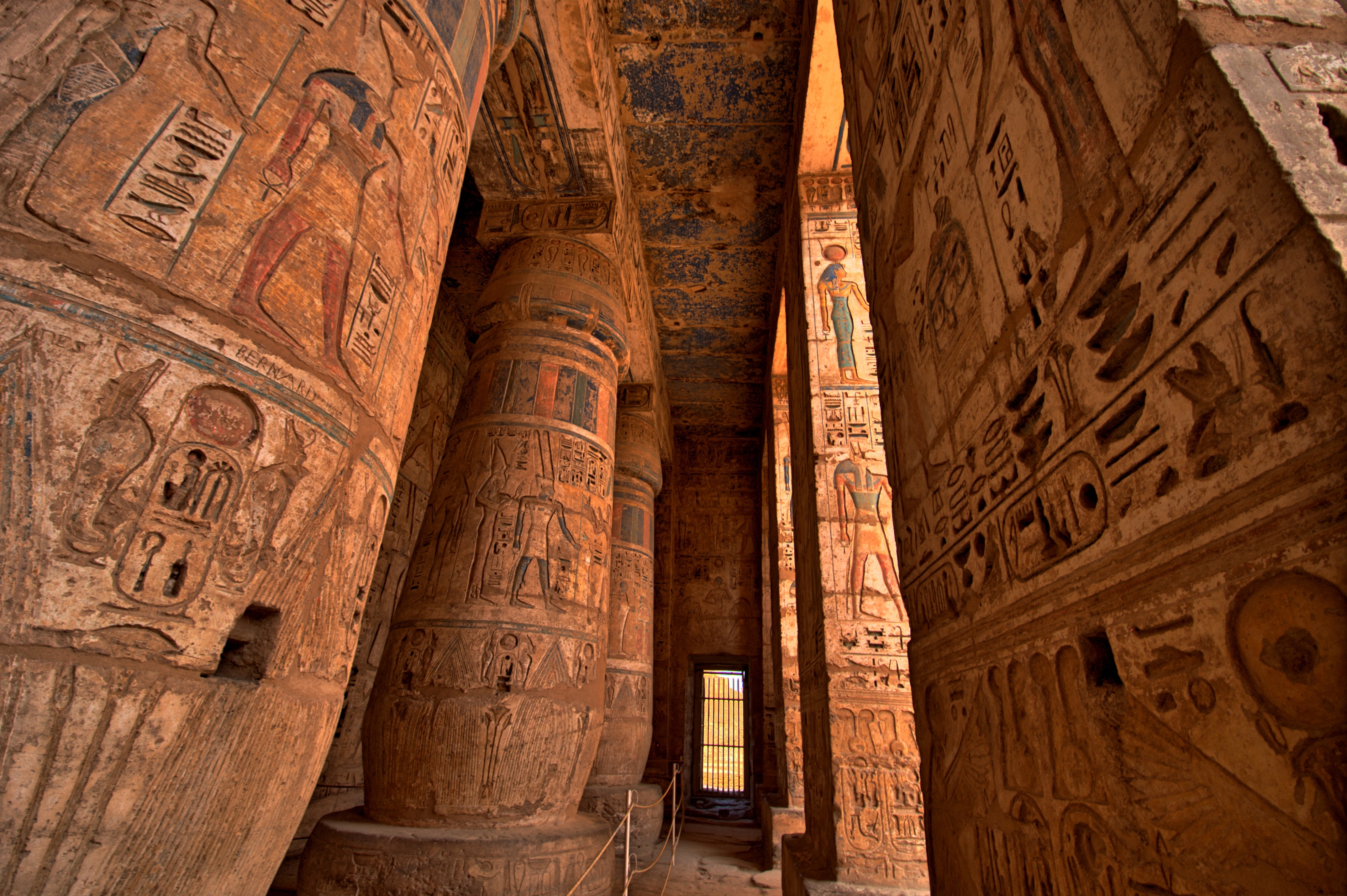 Majestætiske søjler og vægge dækket af hieroglyffer og relieffer inde i Medinet Habu templet i Luxor, Egypten