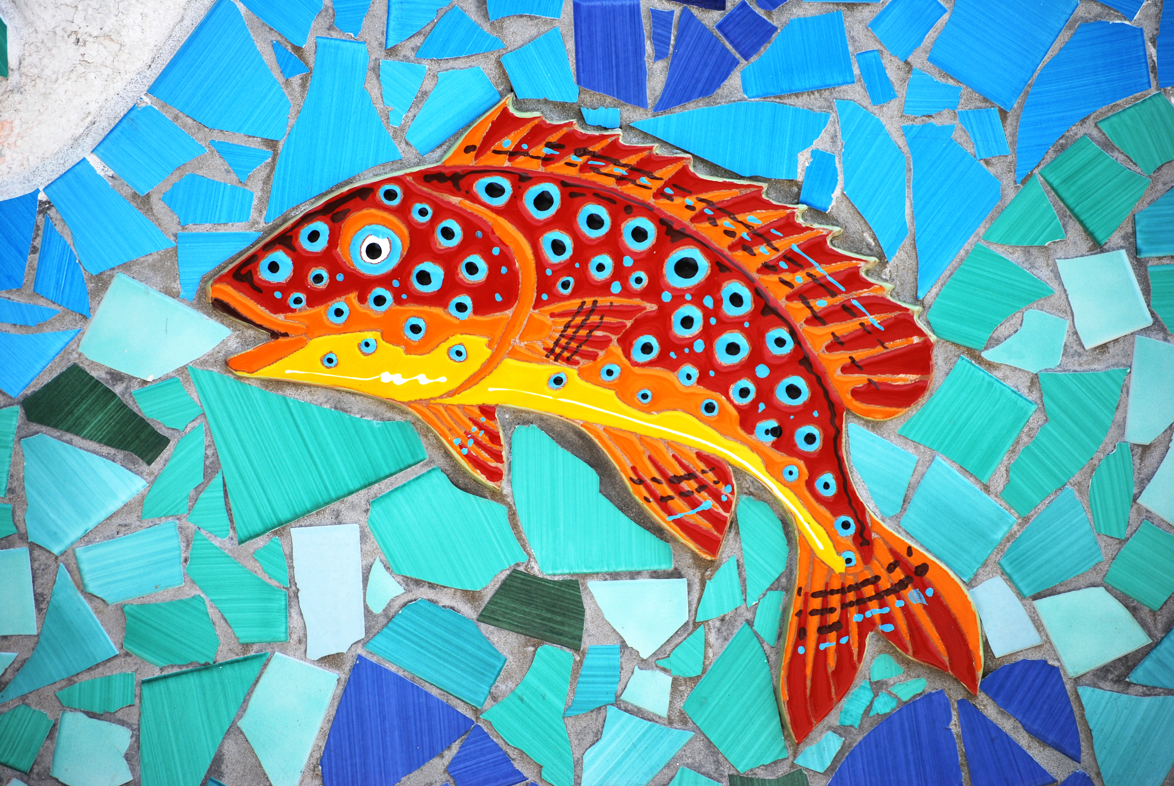 Farverig mosaik fisk på væg med italienske keramiske fliser i blå og orange