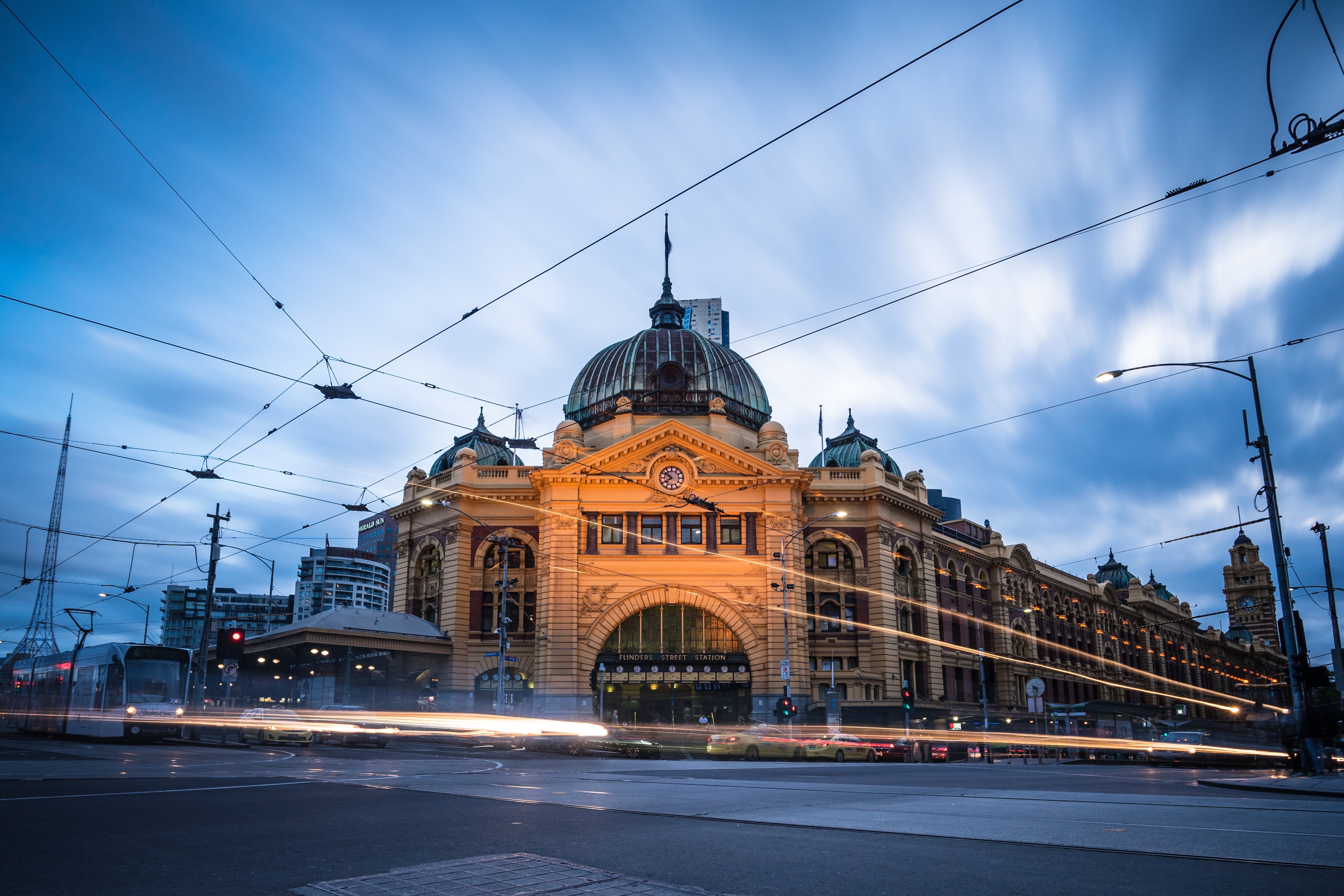 Melbourne Flinders Street Station oplyst ved skumring med sporvogne og viktoriansk arkitektur