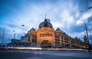 Melbourne Flinders Street Station oplyst ved skumring med sporvogne og viktoriansk arkitektur