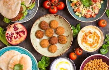 Traditionel mellemøstlig mezze med falafel, hummus, tabbouleh salat, pitabrød og granatæble serveret i farverige skåle