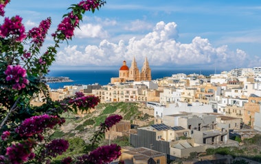 Malerisk udsigt over Mellieha sognekirke og kystlandsby på Malta med azurblåt Middelhav i baggrunden