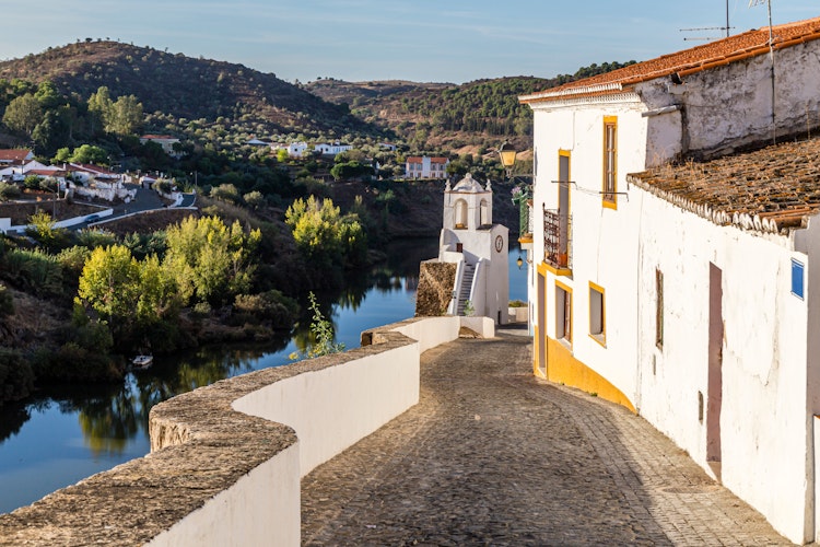Historisk brolagt gade i Mertola Portugal med udsigt over Guadiana floden og traditionelle hvide huse