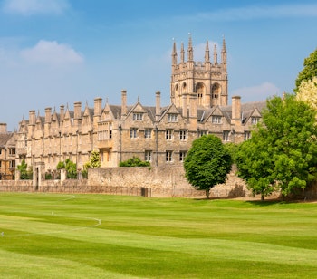 Det historiske Merton College med sin imponerende middelalderarkitektur og karakteristiske tårn omgivet af velholdte grønne plæner på Oxford Universitet i England