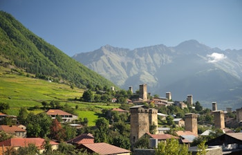 Historiske Mestia landsby med traditionelle svanetiske tårne omgivet af grønne marker og majestætiske bjerge i Svaneti-regionen, Georgien