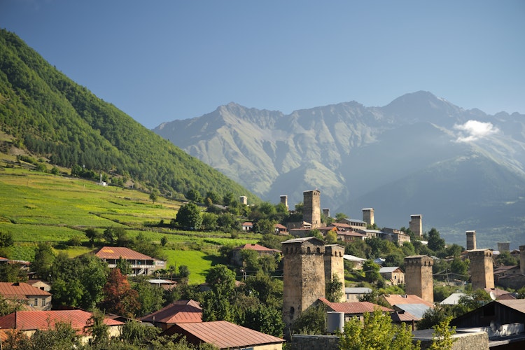 Historiske Mestia landsby med traditionelle svanetiske tårne omgivet af grønne marker og majestætiske bjerge i Svaneti-regionen, Georgien