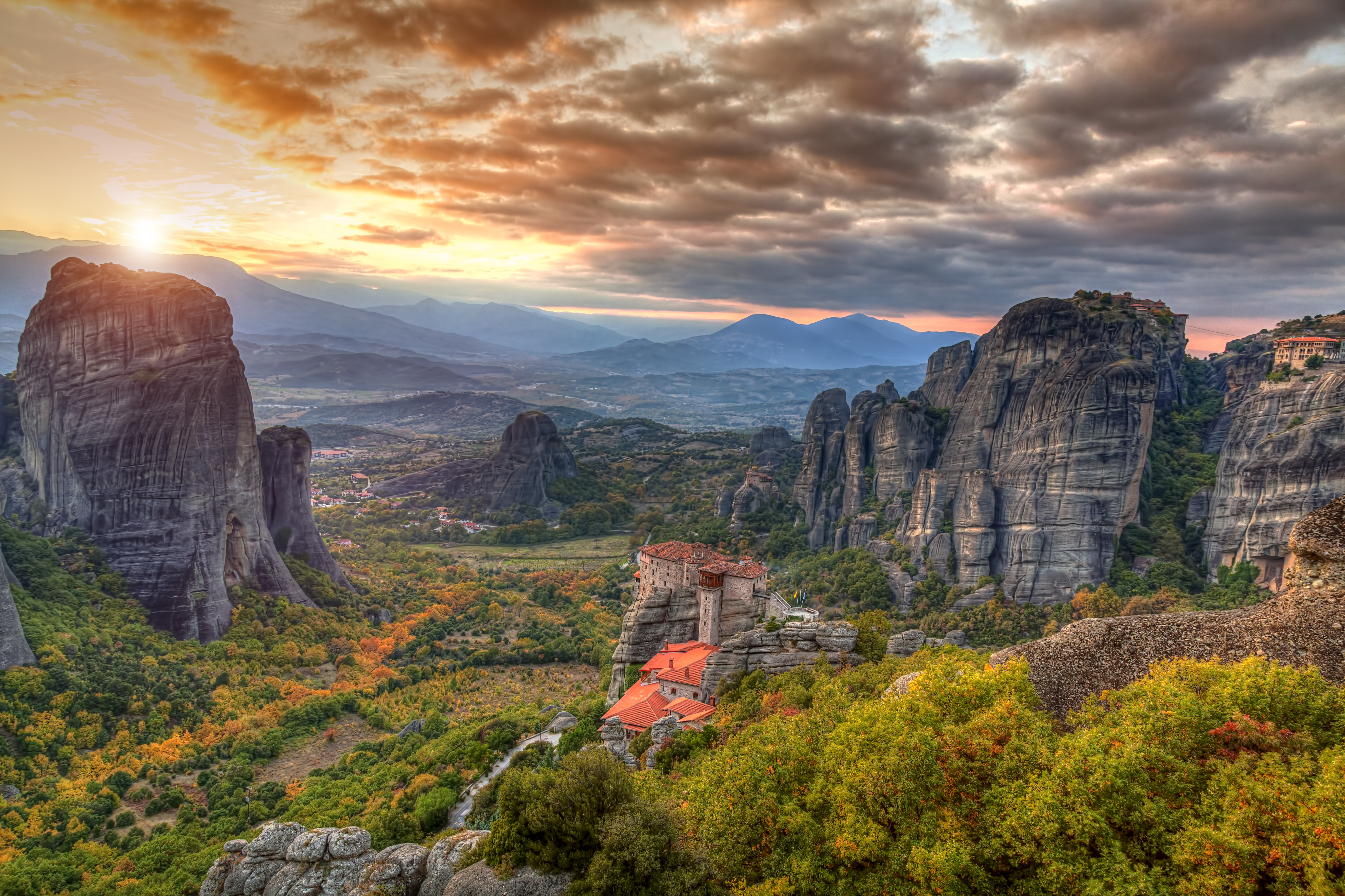 Betagende solnedgang over Meteoras klosterby med dramatiske klippeformationer og efterårsfarver i Kalambaka, Grækenland