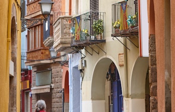 Charmerende brolagt gade med farverige historiske bygninger i middelalderbyen Castello de Empuries i Girona-provinsen, Catalonien - en velbevarede middelalderby tæt på Costa Brava