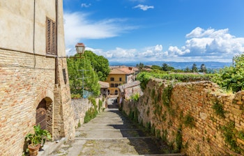 Historisk byudsigt fra middelalderlige San Gimignano i Toscana med smalle stengader og charmerende bygninger med udsigt over det toscanske landskab