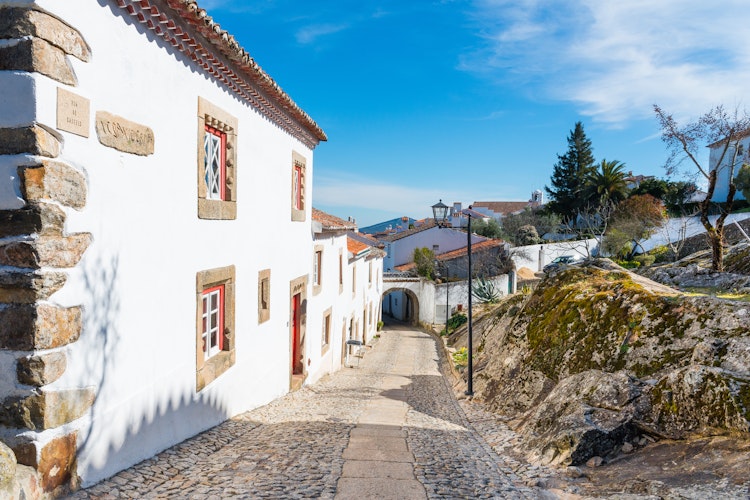 Charmerende brostensbelagt gade i middelalderbyen Marvao i Alentejo-regionen, Portugal, med traditionelle hvidkalkede huse og historisk arkitektur