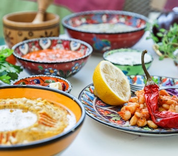 Traditionel middelhavs mezze med hummus, babaganoush og krydrede dips serveret i farverige keramikskåle