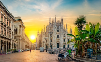 Den berømte Duomo-katedral på Piazza del Duomo i Milano badet i gyldent solopgangslys, der fremhæver den gotiske arkitektur i Norditalien
