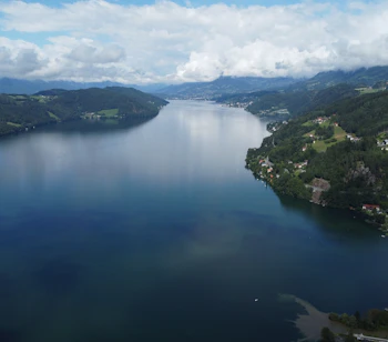 Luftfoto af det smukke Millstätter See omgivet af grønne bjerge og østrigske landsbyer