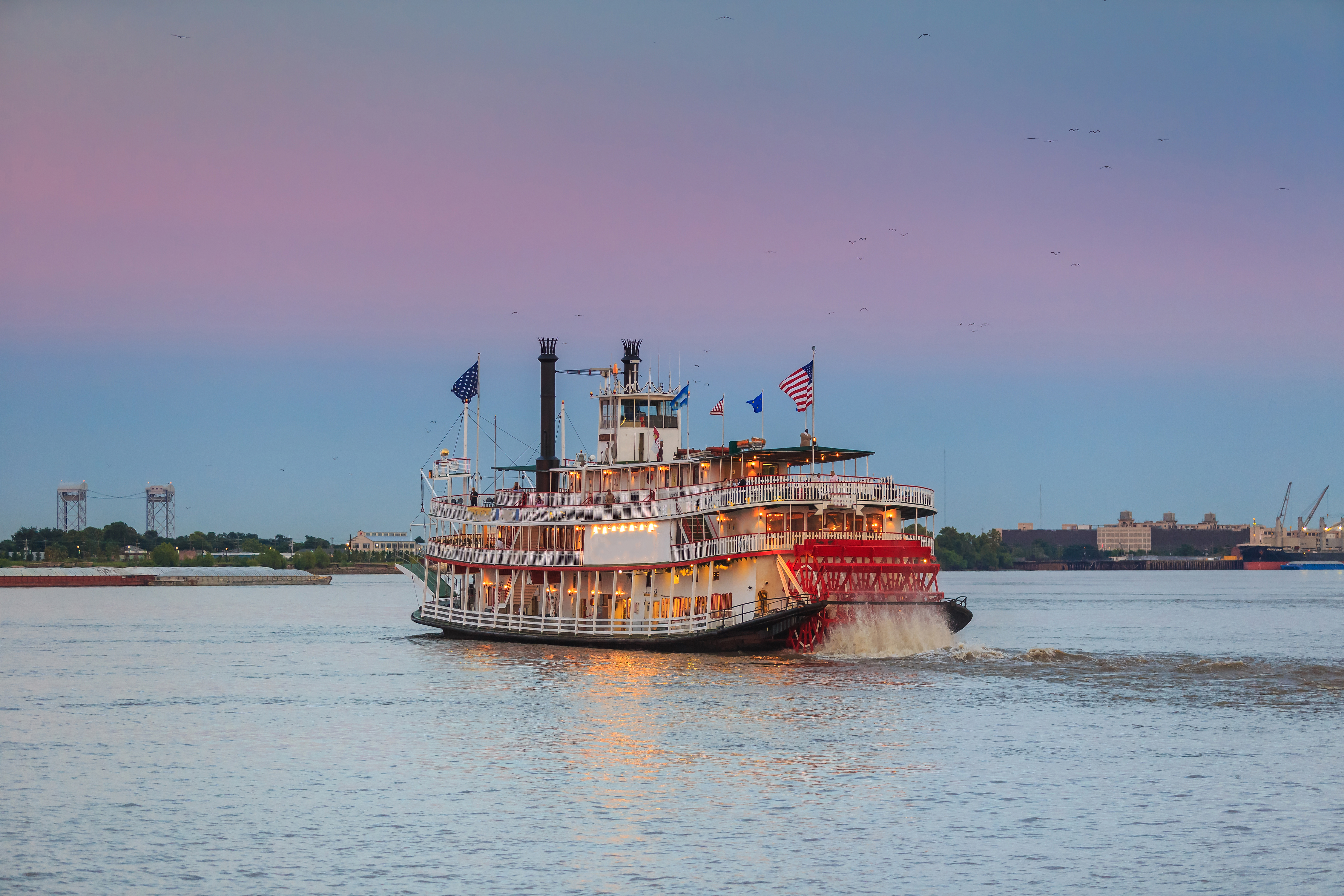 Traditionel Mississippi dampbåd sejler gennem New Orleans havn ved solnedgang