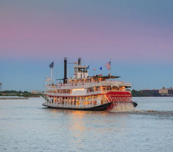 Traditionel Mississippi dampbåd sejler gennem New Orleans havn ved solnedgang