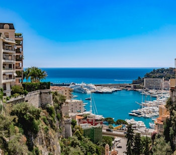 Smuk panoramaudsigt over Monaco by med eksklusiv marina og historiske bygninger placeret majestætisk på Le Rocher-klippen ved Middelhavet