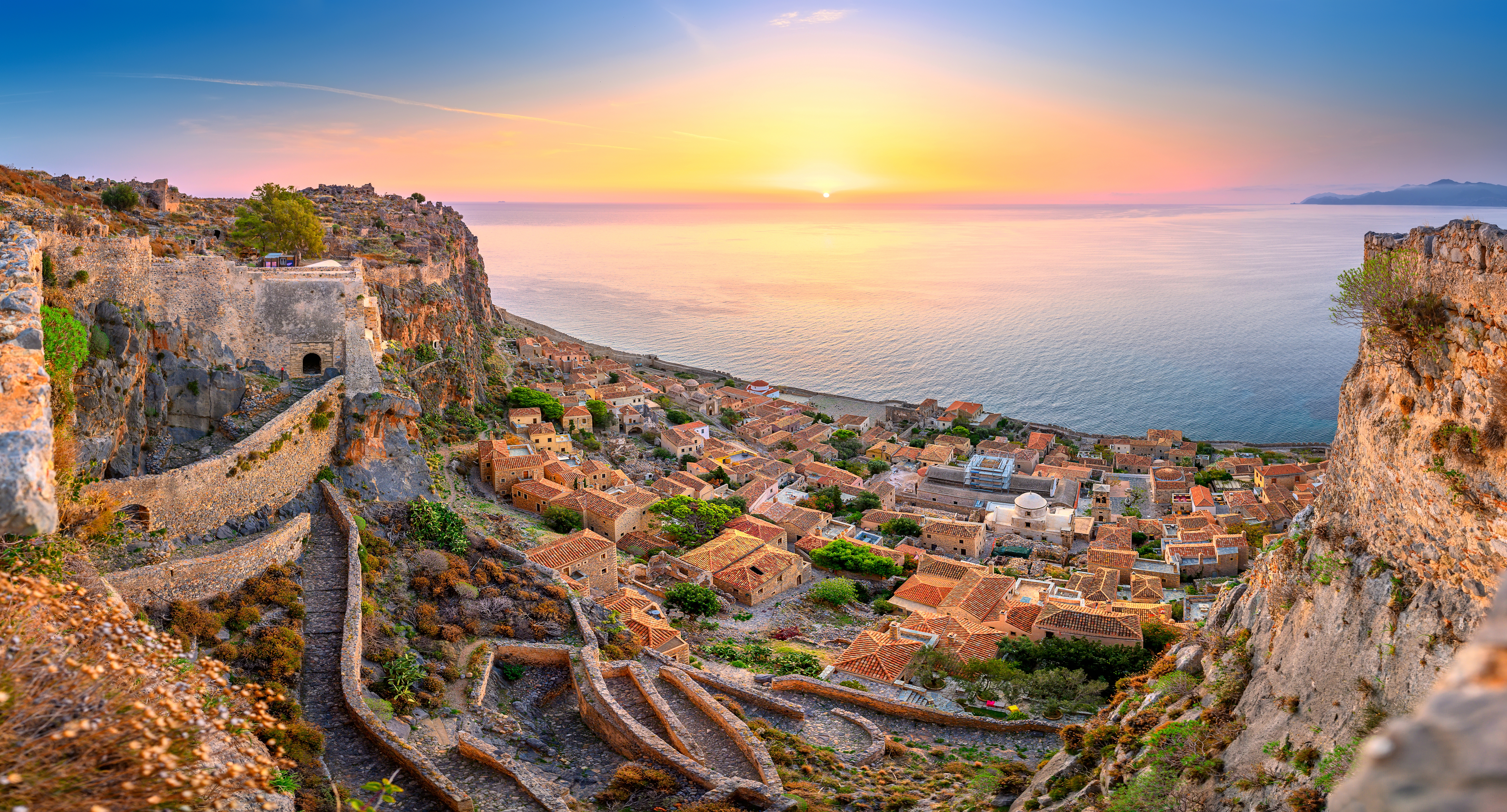 Betagende panoramaudsigt over den middelalderlige fæstningsby Monemvasia bygget på klipper ved solopgang med udsigt over Middelhavet i Peloponnes, Grækenland