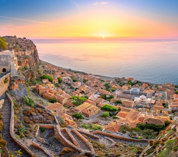 Betagende panoramaudsigt over den middelalderlige fæstningsby Monemvasia bygget på klipper ved solopgang med udsigt over Middelhavet i Peloponnes, Grækenland