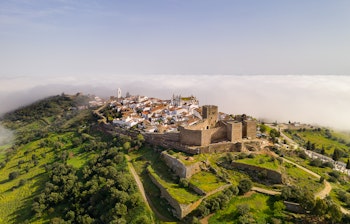 Luftfoto af den middelalderlige landsby Monsaraz i Portugal med slot og hvide huse på bakketop