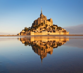Mont Saint-Michel klosteret spejler sig i vandet ved solnedgang i Normandiet, Frankrig - historisk seværdighed