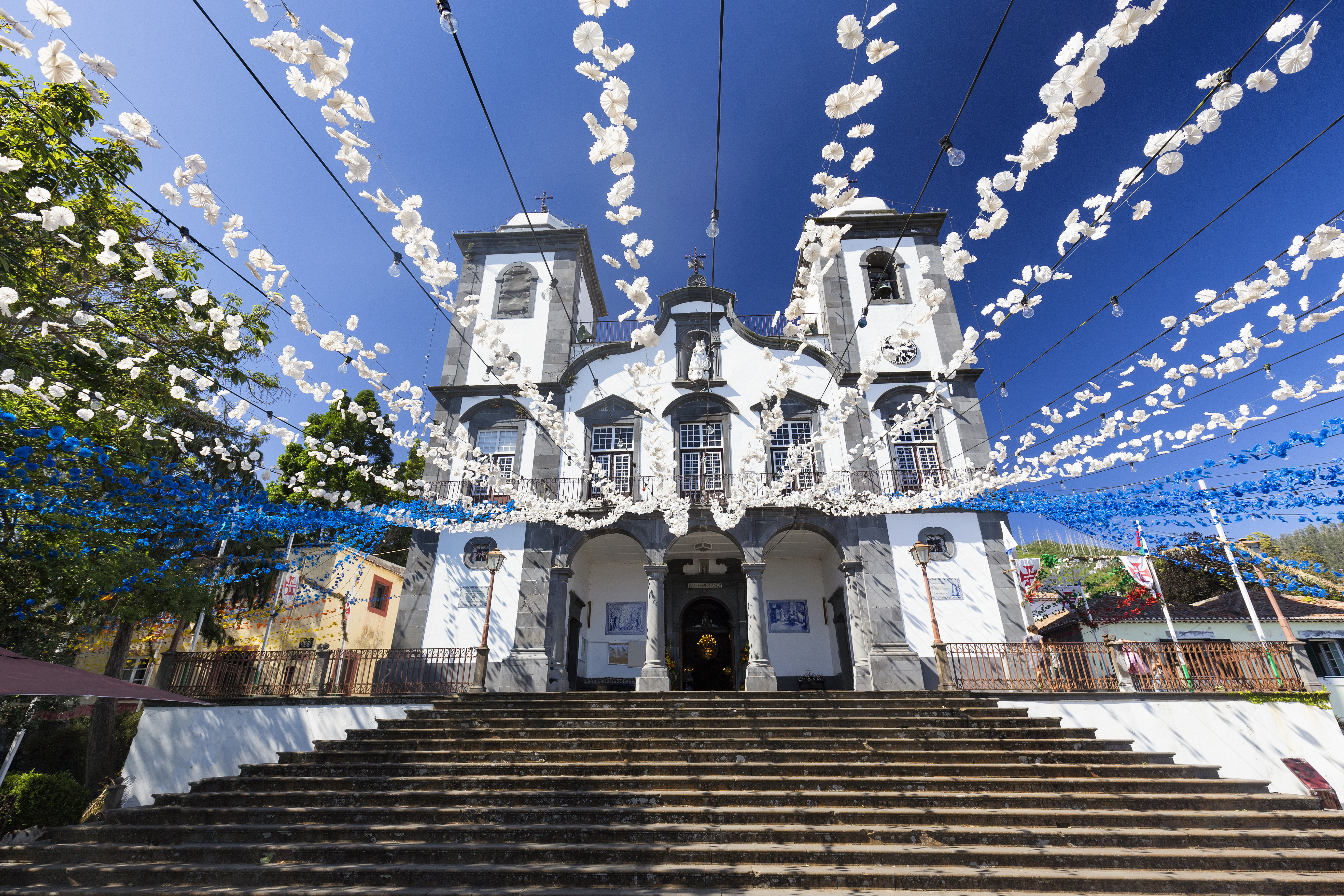 Den smukke Monte Kirke i Funchal pyntet med blå og hvide blomsterdekorationer henover indgangen og den storslåede stentrappe på Madeira, Portugal