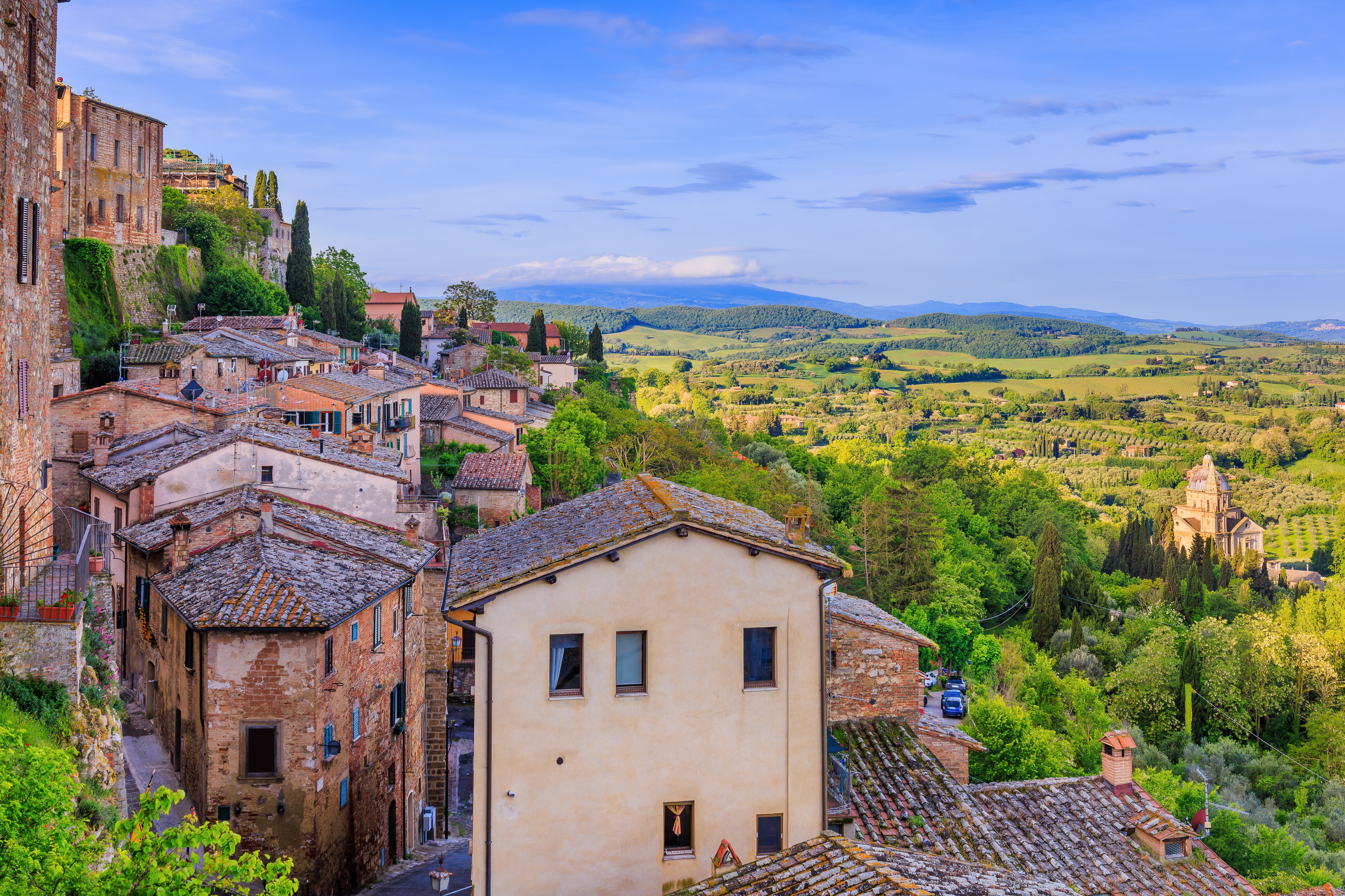 Panoramaudsigt over den middelalderlige bjergby Montepulciano med tegltagshuse og det smukke toscanske landskab i baggrunden, Italien