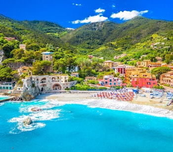 Panoramaudsigt over Monterosso al Mare i Cinque Terre med turkisblåt hav, gylden sandstrand og farverige bygninger langs den italienske riviera