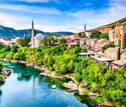 Idyllisk morgenudsigt over den historiske by Mostar med den smukke moské og traditionel arkitektur langs den smaragdgrønne Neretva-flod