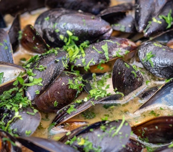 Moules-frites serveret i sort gryde med sprøde pommes frites - den ikoniske belgiske nationalret fra Bruxelles' køkken
