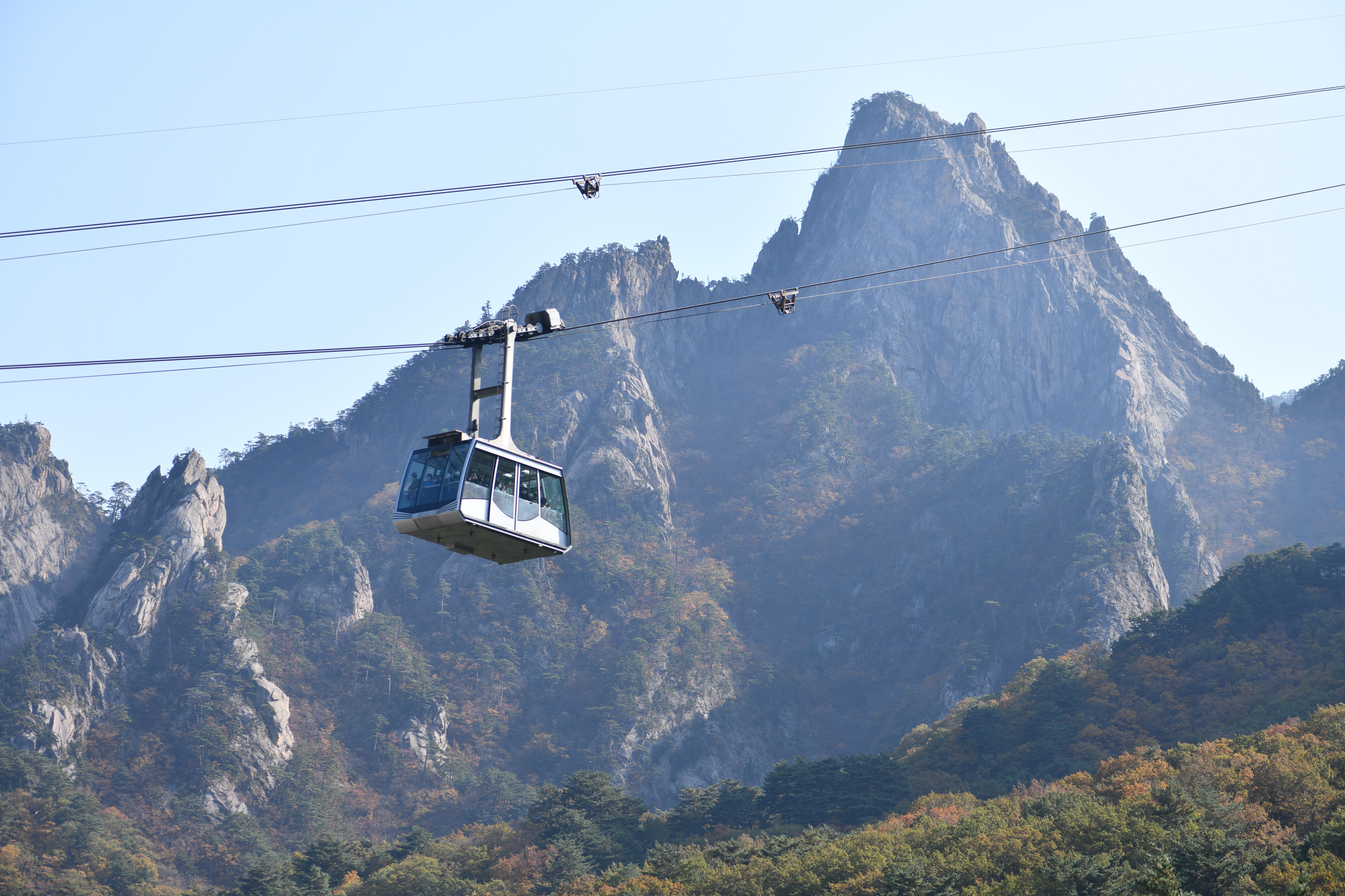 Gwongeumseong kabelbane svæver over de majestætiske bjergtinder i Mt. Seorak Nationalpark i Sydkorea med en klar blå himmel i baggrunden