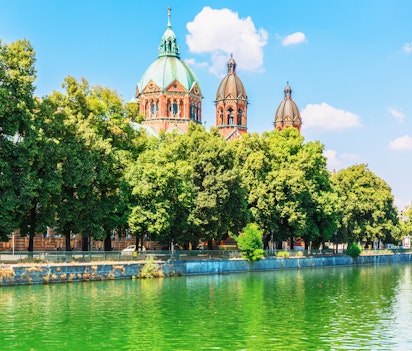Idyllisk sommerudsigt over Isar-flodens bred med historiske bygninger i Münchens gamle bydel, Bayern