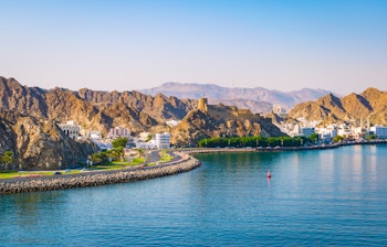 Smuk udsigt over Muscats kystlinje med majestætiske bjerge, azurblåt hav og traditionel omansk arkitektur