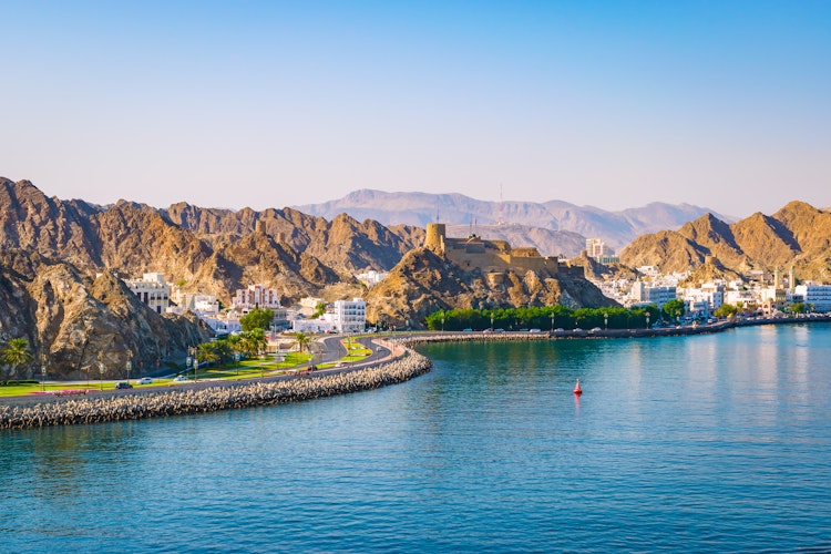 Smuk udsigt over Muscats kystlinje med majestætiske bjerge, azurblåt hav og traditionel omansk arkitektur