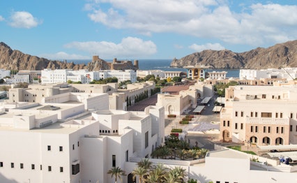 Betagende udsigt over Muscat, Omans hovedstad, med dens karakteristiske hvide bygninger der ligger malerisk mellem dramatiske bjerge og rå klippeformationer ved kysten