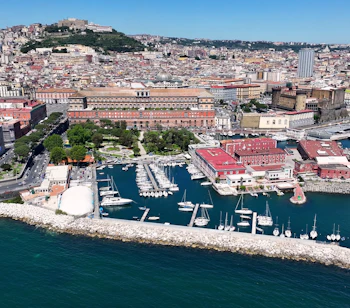 Luftfoto over Napoli med det Kongelige Palads, marina med sejlbåde og den smukke kystlinje ved Napoli-bugten i Italien