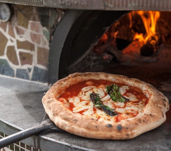 Autentisk napolitansk Margherita pizza tages ud af den træfyrede stenovn i Napoli, Italien