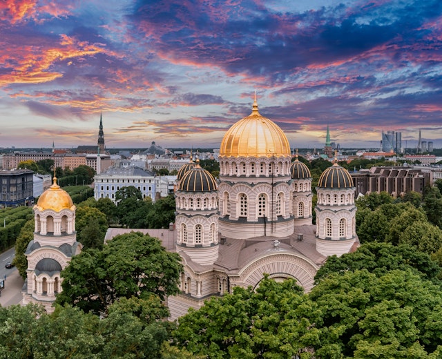 Luftfoto af Kristi Fødsels Katedral i Riga med gylden kuppel der skinner i solnedgangen over Letlands hovedstad