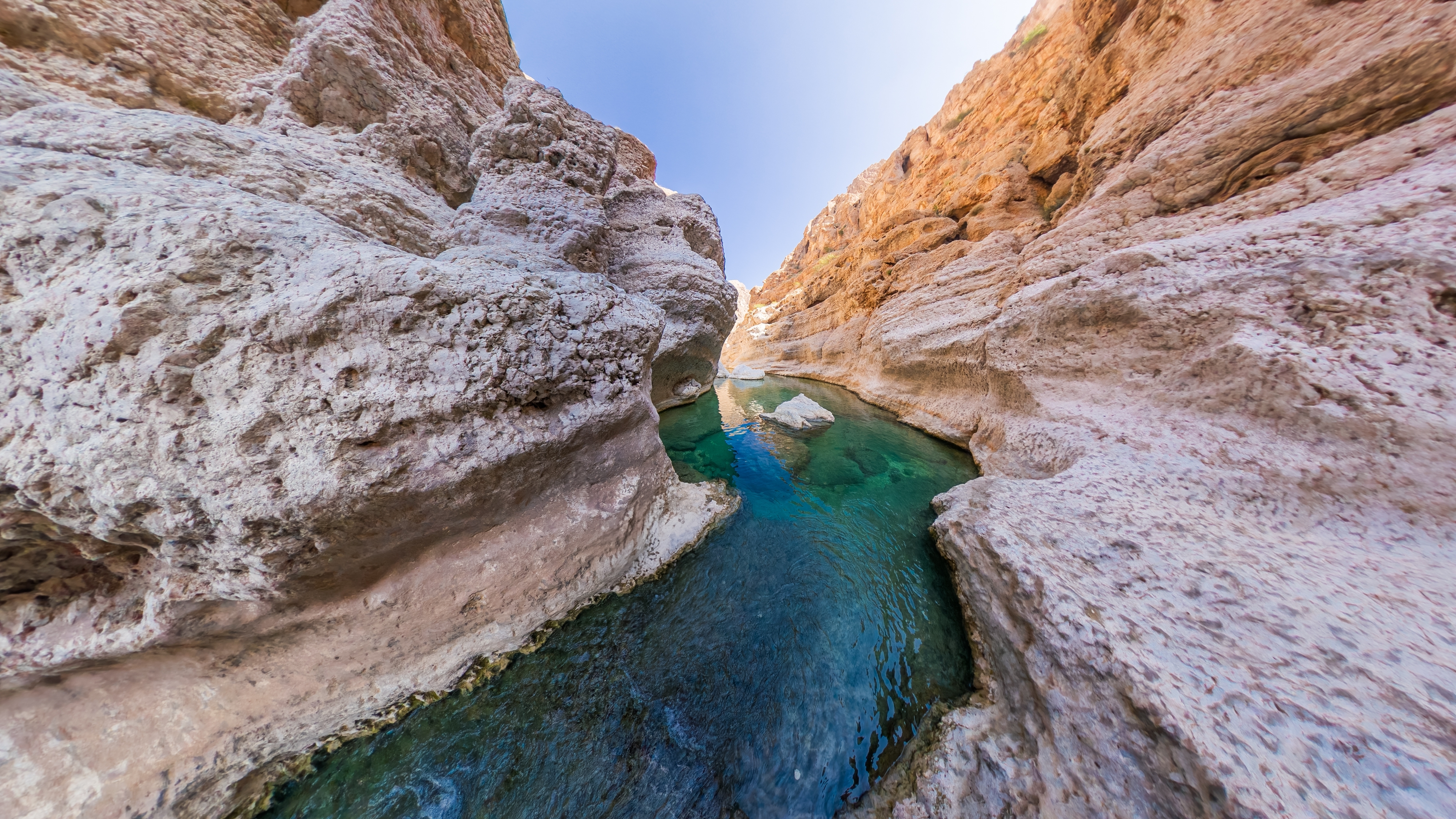 Idyllisk naturlig pool i Wadi Hawer oasen omgivet af majestætiske klippevægge i Omans betagende bjerglandskab
