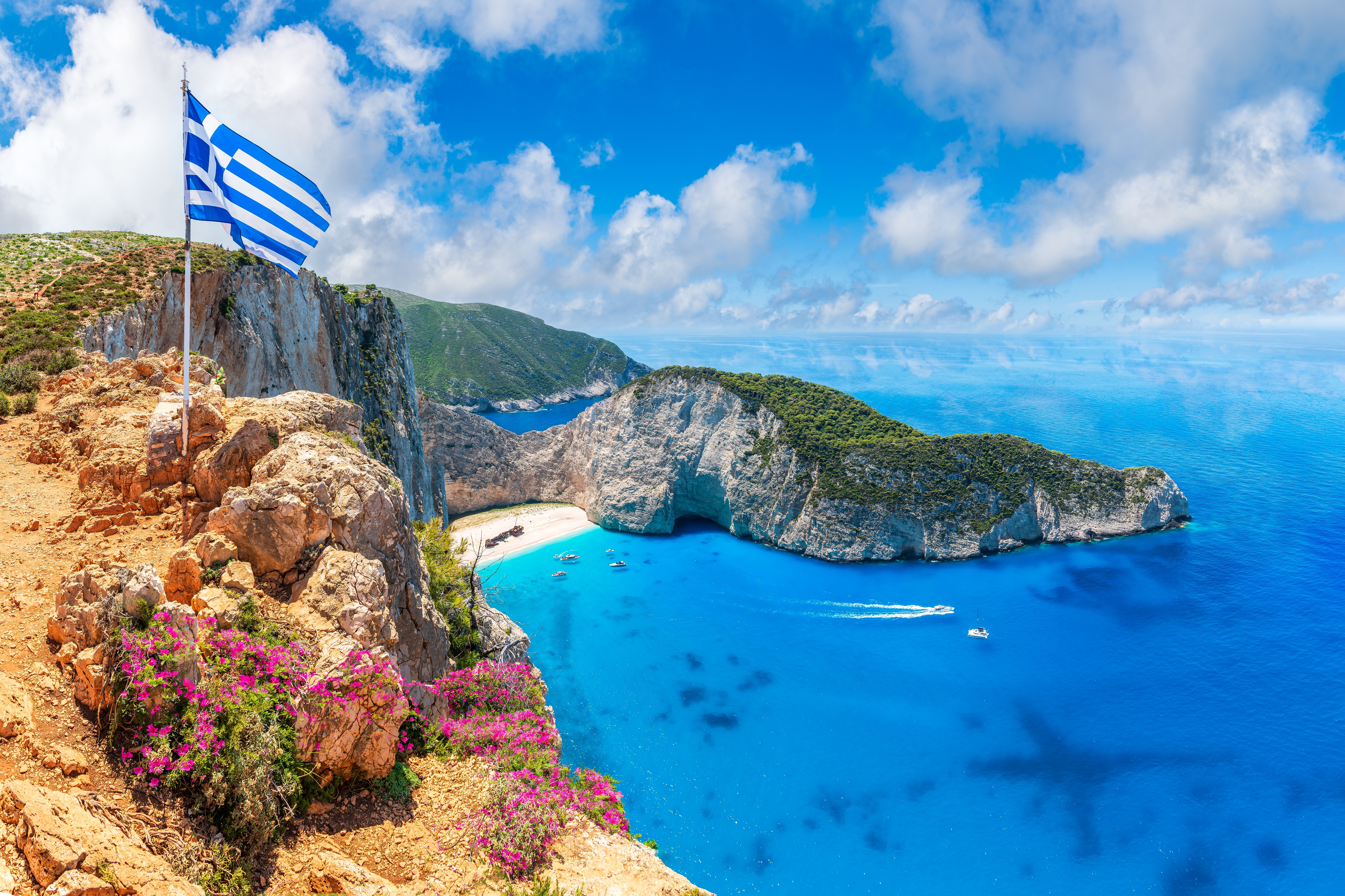 Den berømte Navagio strand med skibsvrag på Zakynthos, Grækenland, med krystalklart turkisblåt vand og det græske flag på klippen