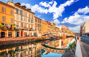 Den historiske Naviglio Grande kanal i Milano med farverige bygninger og bro ved solopgang