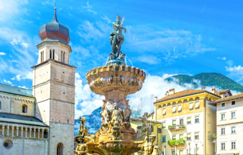 Den barokke Neptun-fontæne på Piazza Duomo i Trento, Italien, med katedraltårnet og Alperne i baggrunden