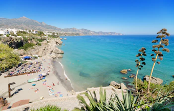 Smuk strand i Nerja på Costa del Sol med turkisblåt vand og bjerglandskab