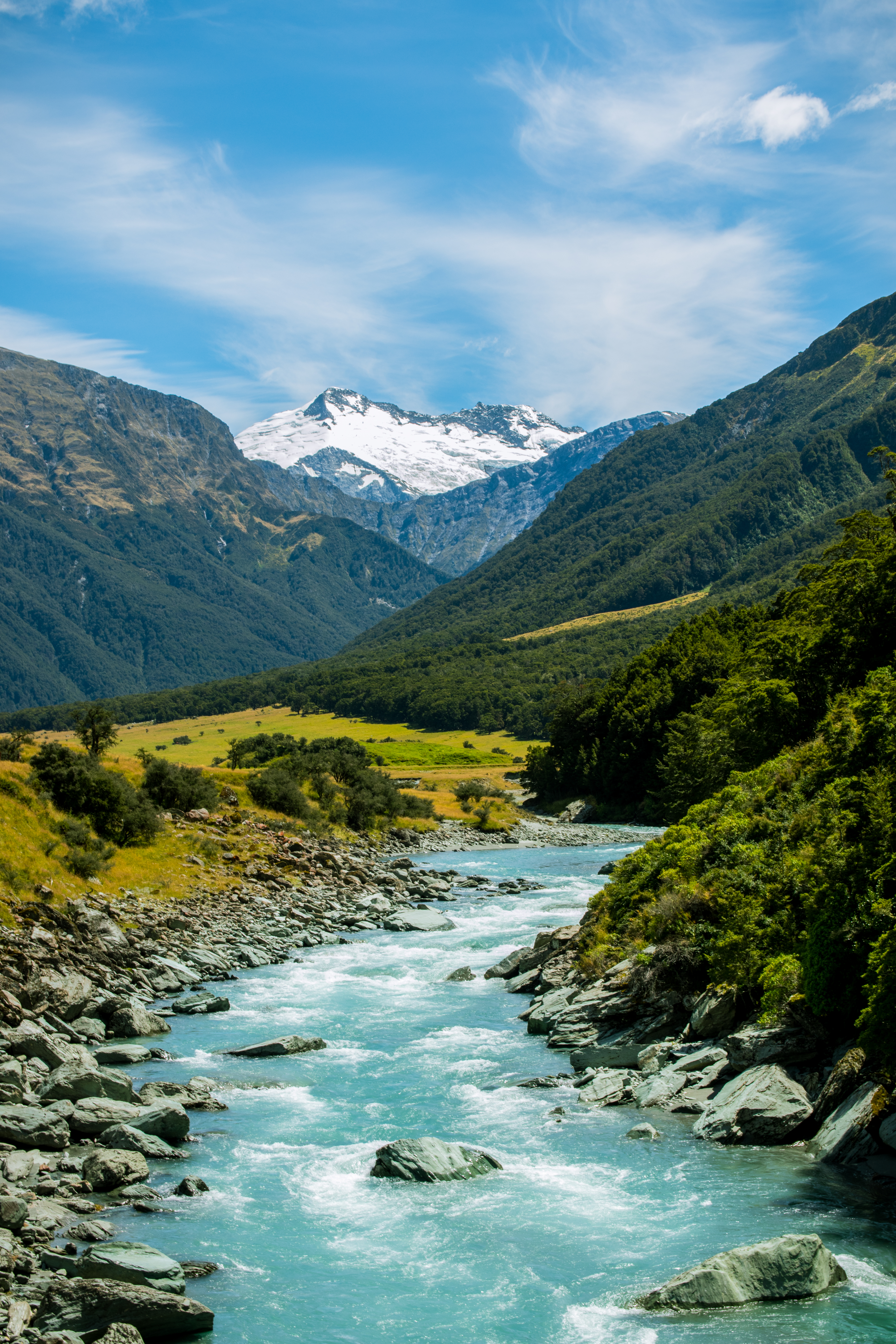 Smuk bjergdal med turkis flod og sneklaedte toppe i New Zealand