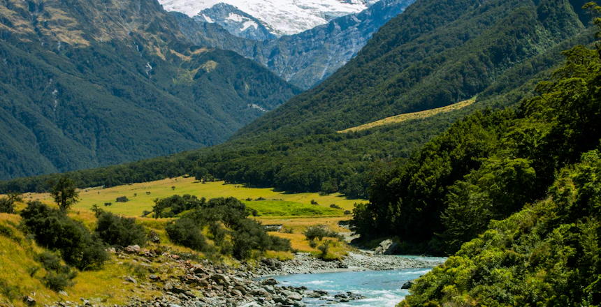 Smuk bjergdal med turkis flod og sneklaedte toppe i New Zealand