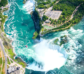 Spektakulært luftfoto af Niagara Falls med turkisblåt vand og regnbue i tågen