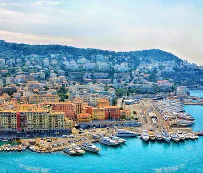 Smuk udsigt over Nice havn med farverige bygninger og luksusyachter på den franske riviera