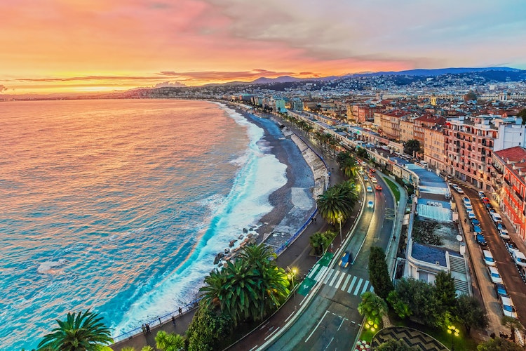 Malerisk aftenudsigt over Nice på den franske riviera med byens lys, middelhavet og alperne i skumringen